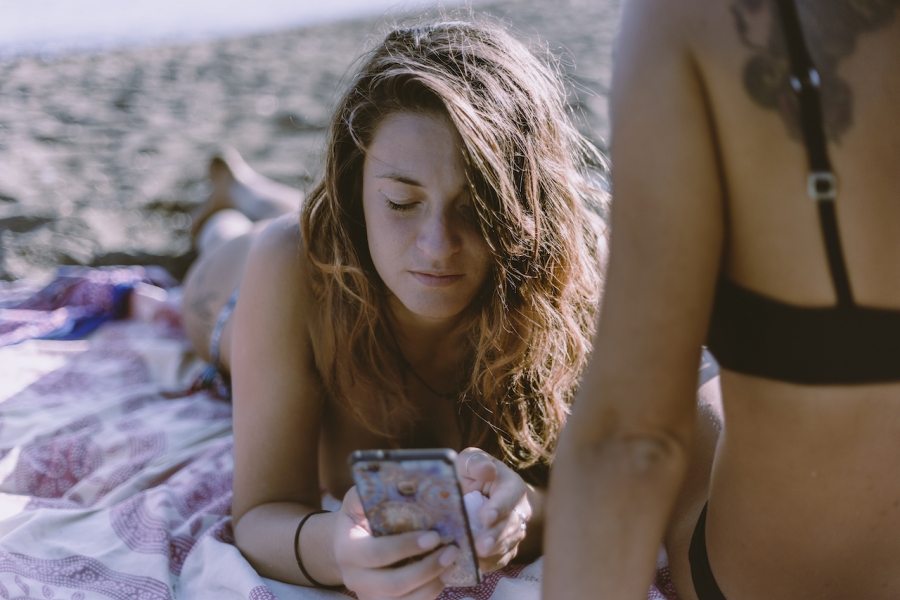Tânără cu smartphone pe plajă